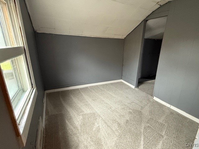 empty room featuring light colored carpet and lofted ceiling