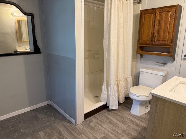 bathroom featuring wood-type flooring, vanity, toilet, and walk in shower