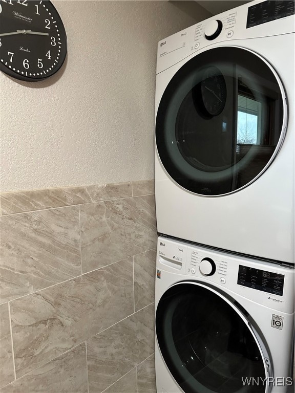 clothes washing area featuring stacked washing maching and dryer