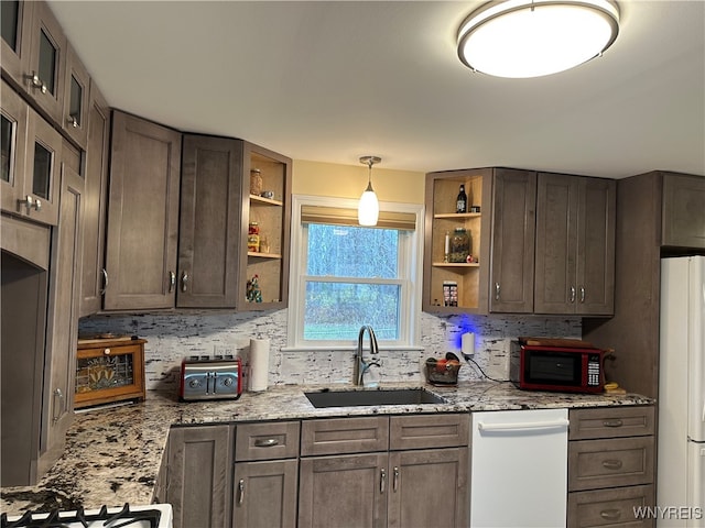 kitchen featuring light stone counters, white appliances, dark brown cabinetry, sink, and pendant lighting