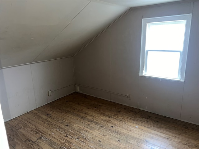 additional living space with hardwood / wood-style floors and vaulted ceiling