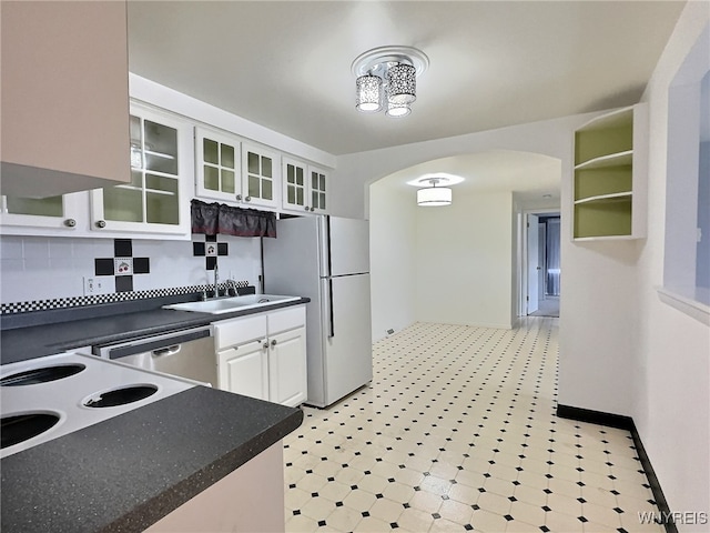 kitchen featuring backsplash, white cabinets, sink, stainless steel dishwasher, and white fridge