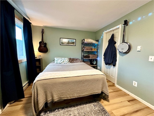 bedroom with a baseboard radiator and light hardwood / wood-style flooring