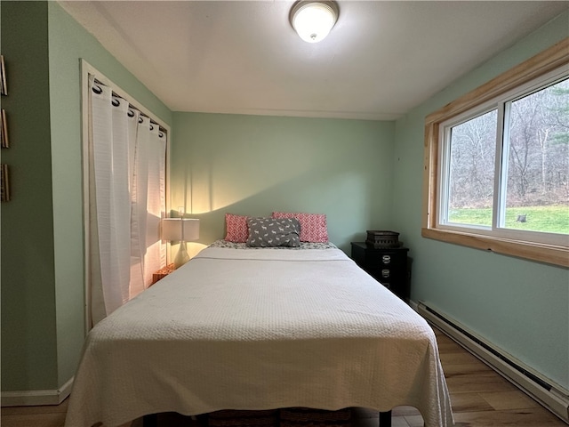 bedroom featuring baseboard heating and wood-type flooring