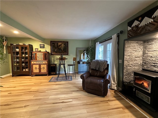 sitting room featuring a wood stove and light hardwood / wood-style flooring