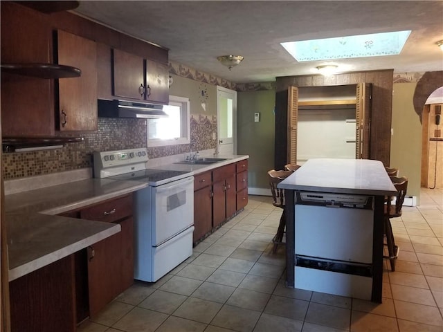 kitchen featuring a breakfast bar area, a skylight, sink, and white electric range