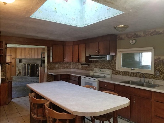 kitchen with light countertops, white electric range, brown cabinetry, a sink, and under cabinet range hood