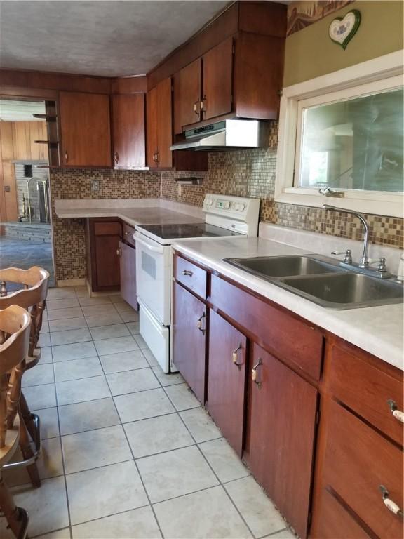 kitchen featuring white range with electric cooktop, tasteful backsplash, light countertops, a sink, and under cabinet range hood