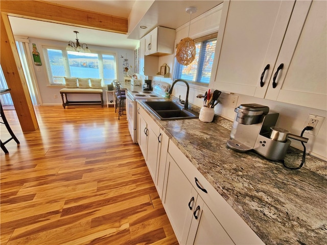 kitchen with light wood-type flooring, sink, pendant lighting, white cabinets, and a chandelier