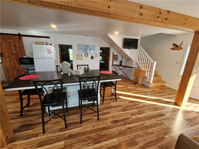 dining space with wood-type flooring and a barn door