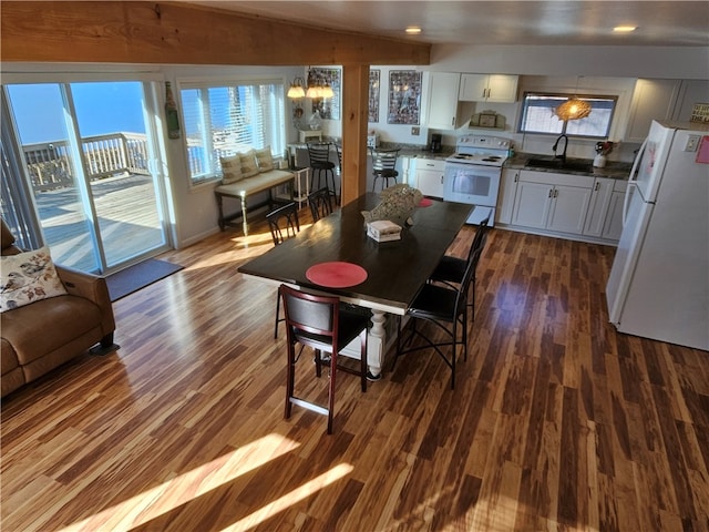 dining area featuring lofted ceiling, an inviting chandelier, dark wood-type flooring, and sink