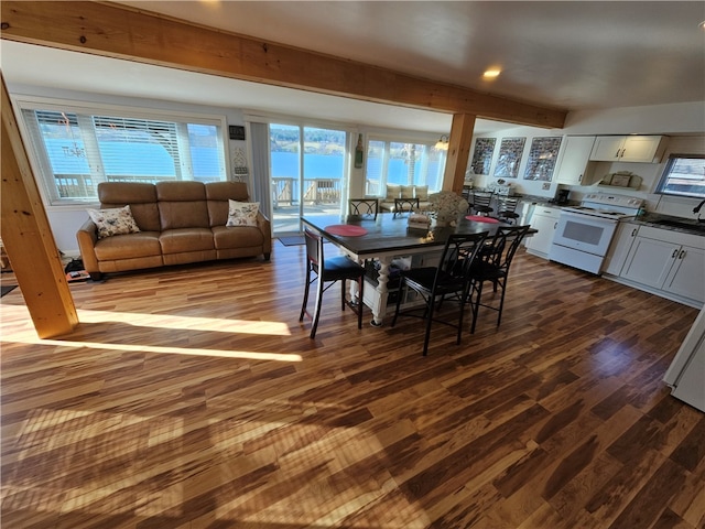 dining room featuring beam ceiling, hardwood / wood-style flooring, a wealth of natural light, and sink