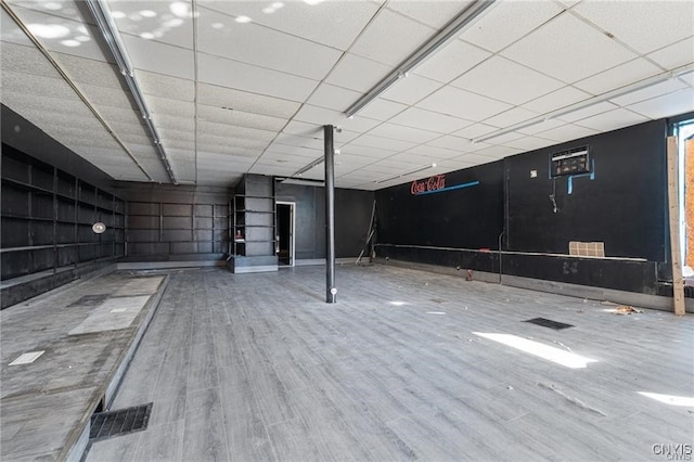 basement with wood-type flooring and a paneled ceiling