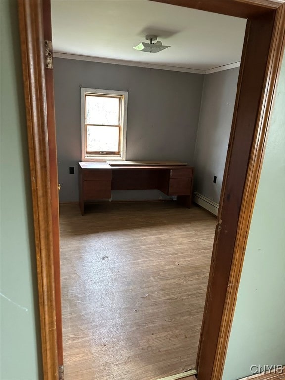 unfurnished room featuring crown molding, a baseboard heating unit, and light wood-type flooring