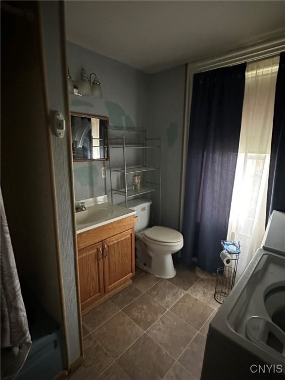 bathroom featuring washer / clothes dryer, tile patterned flooring, vanity, and toilet