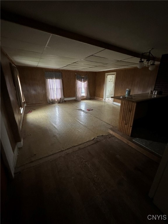 basement with hardwood / wood-style flooring, a drop ceiling, and wood walls