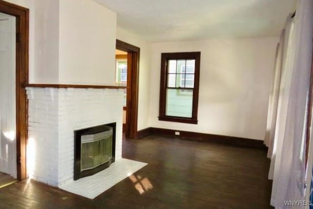 unfurnished living room with dark hardwood / wood-style flooring and a brick fireplace