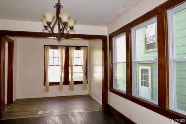 interior space with plenty of natural light, dark wood-type flooring, and a notable chandelier