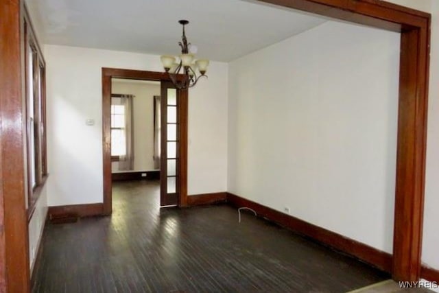 unfurnished room featuring dark hardwood / wood-style flooring and an inviting chandelier