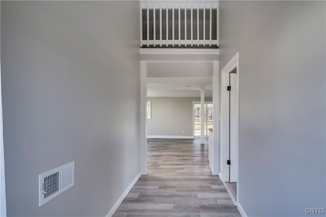 hallway with a towering ceiling and light wood-type flooring