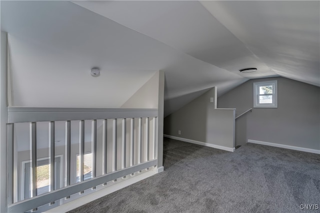 additional living space featuring dark carpet and vaulted ceiling