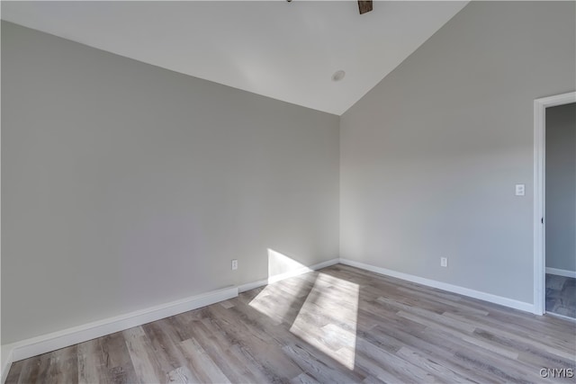 spare room with light hardwood / wood-style floors and high vaulted ceiling