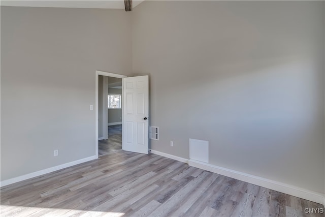 unfurnished room featuring a high ceiling and light wood-type flooring