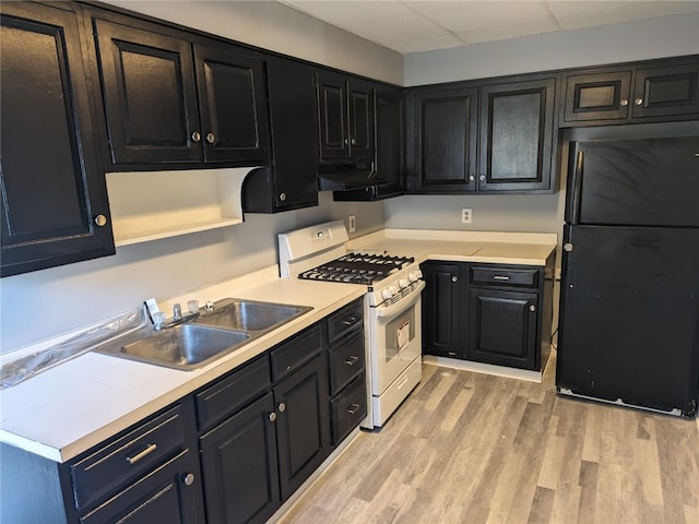 kitchen with white gas range, sink, black refrigerator, and light wood-type flooring