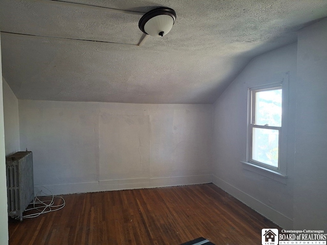 bonus room with radiator heating unit, a textured ceiling, vaulted ceiling, and dark wood-type flooring