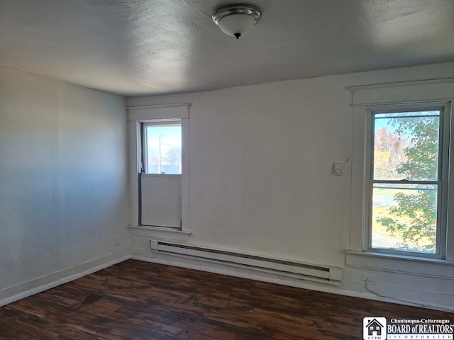 empty room with baseboard heating and dark wood-type flooring