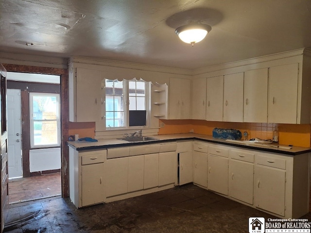 kitchen with decorative backsplash, white cabinetry, and sink