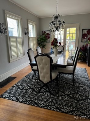 dining room featuring a notable chandelier, plenty of natural light, light hardwood / wood-style floors, and crown molding