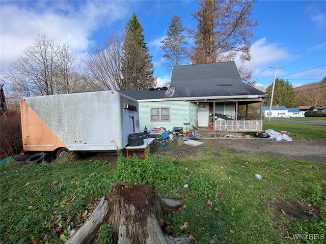 back of property featuring covered porch and a lawn