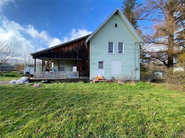 rear view of property featuring a lawn and covered porch