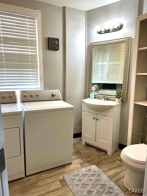 laundry room with separate washer and dryer, sink, and light hardwood / wood-style floors