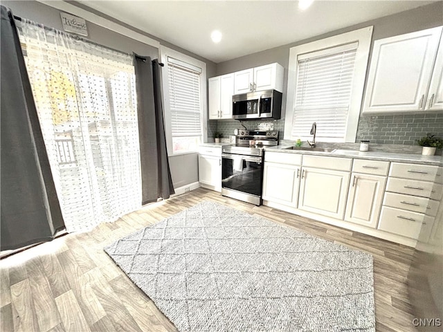 kitchen featuring stainless steel appliances, sink, white cabinets, and light hardwood / wood-style floors