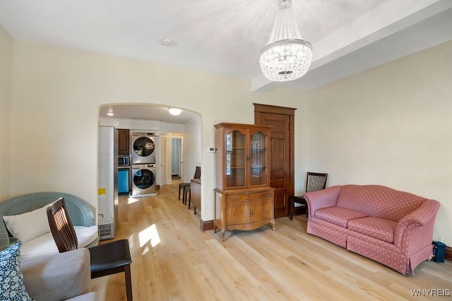 living room featuring a notable chandelier, light hardwood / wood-style floors, and stacked washer / dryer