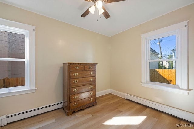 unfurnished room with light wood-type flooring, ceiling fan, and a baseboard heating unit