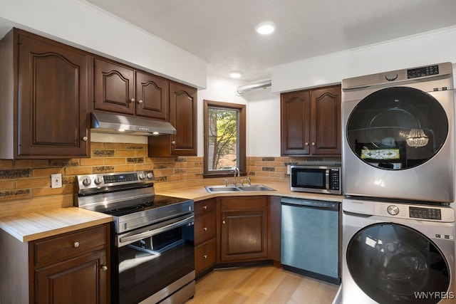 kitchen with appliances with stainless steel finishes, light wood-type flooring, backsplash, sink, and stacked washer and clothes dryer