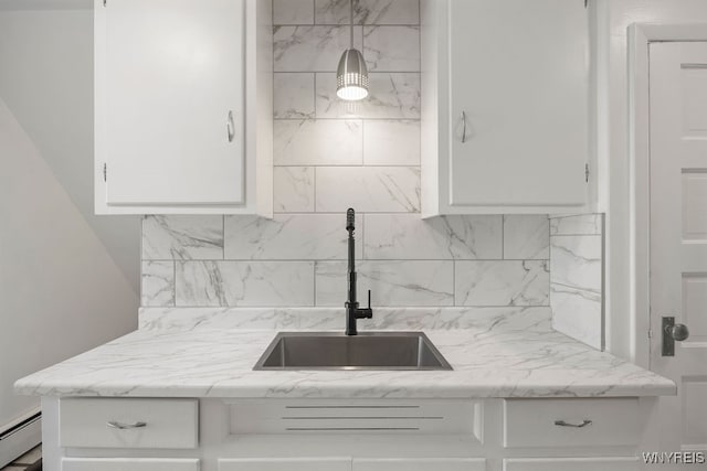 kitchen featuring sink, light stone counters, a baseboard heating unit, pendant lighting, and white cabinets