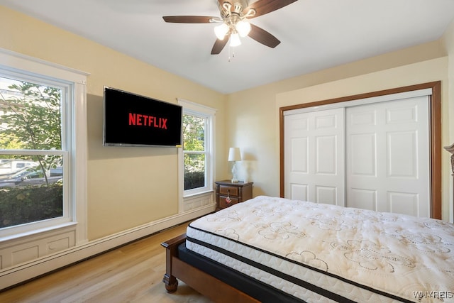 bedroom featuring a closet, multiple windows, ceiling fan, and hardwood / wood-style floors