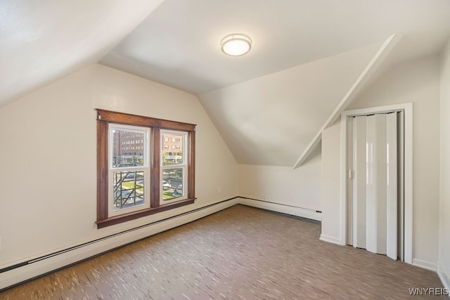 additional living space with a baseboard radiator, light hardwood / wood-style floors, and vaulted ceiling