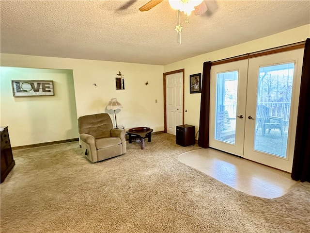 living area with ceiling fan, french doors, light colored carpet, and a textured ceiling