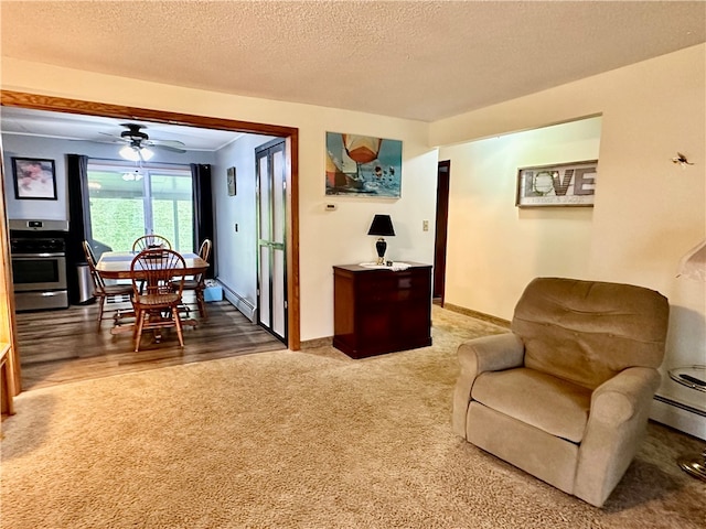 carpeted living room featuring ceiling fan, a textured ceiling, and a baseboard heating unit