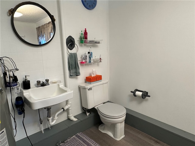 bathroom with wood-type flooring, toilet, sink, and tile walls