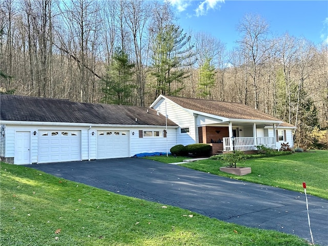 view of front of property featuring covered porch, a front yard, and a garage