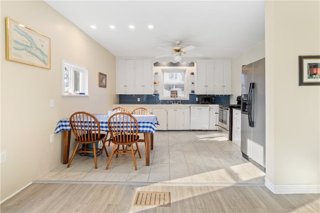 kitchen featuring backsplash, white cabinets, ceiling fan, light wood-type flooring, and stainless steel appliances