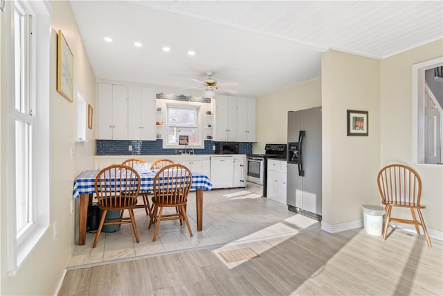 kitchen with white cabinetry, ceiling fan, stainless steel appliances, light hardwood / wood-style flooring, and backsplash