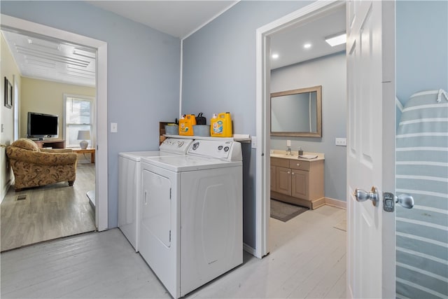 laundry room with independent washer and dryer and light wood-type flooring