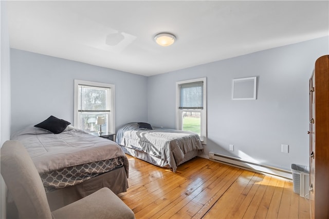 bedroom with light hardwood / wood-style floors and baseboard heating